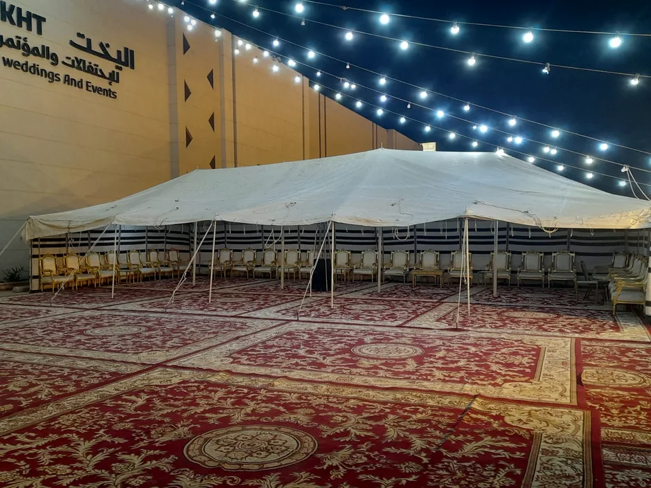 خيمة بيضاء كبيرة مع سجاد وإضاءة خارجية مسائية